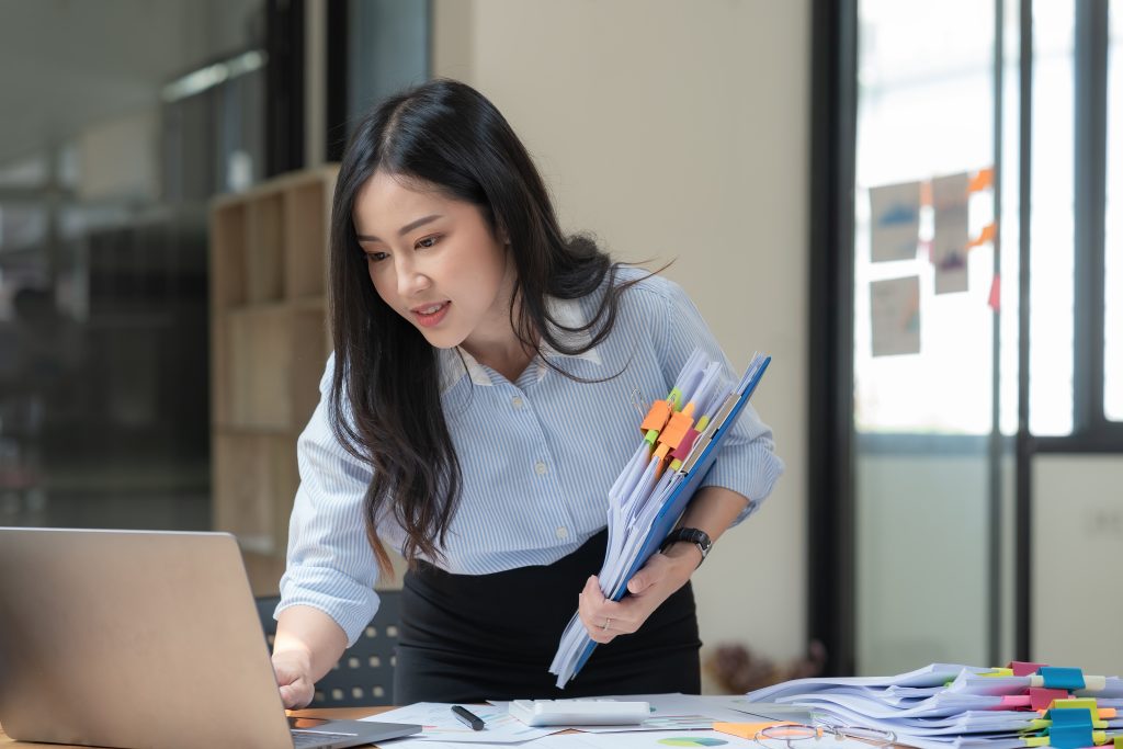 Woman in an office diligently working while carrying a clipboard