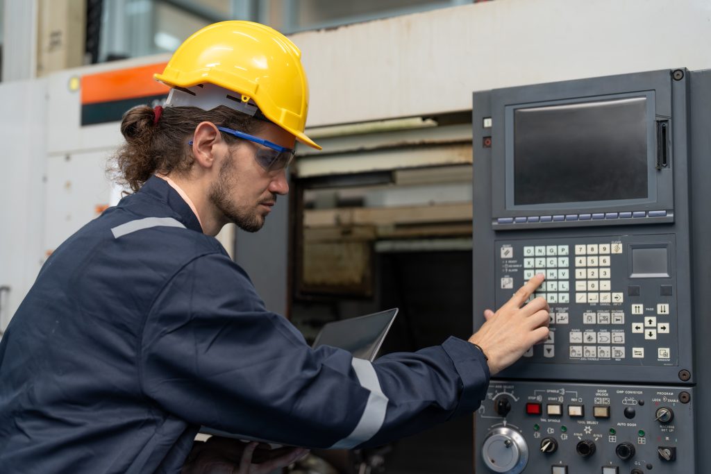 Man with a hardhat operating an industrial machine 