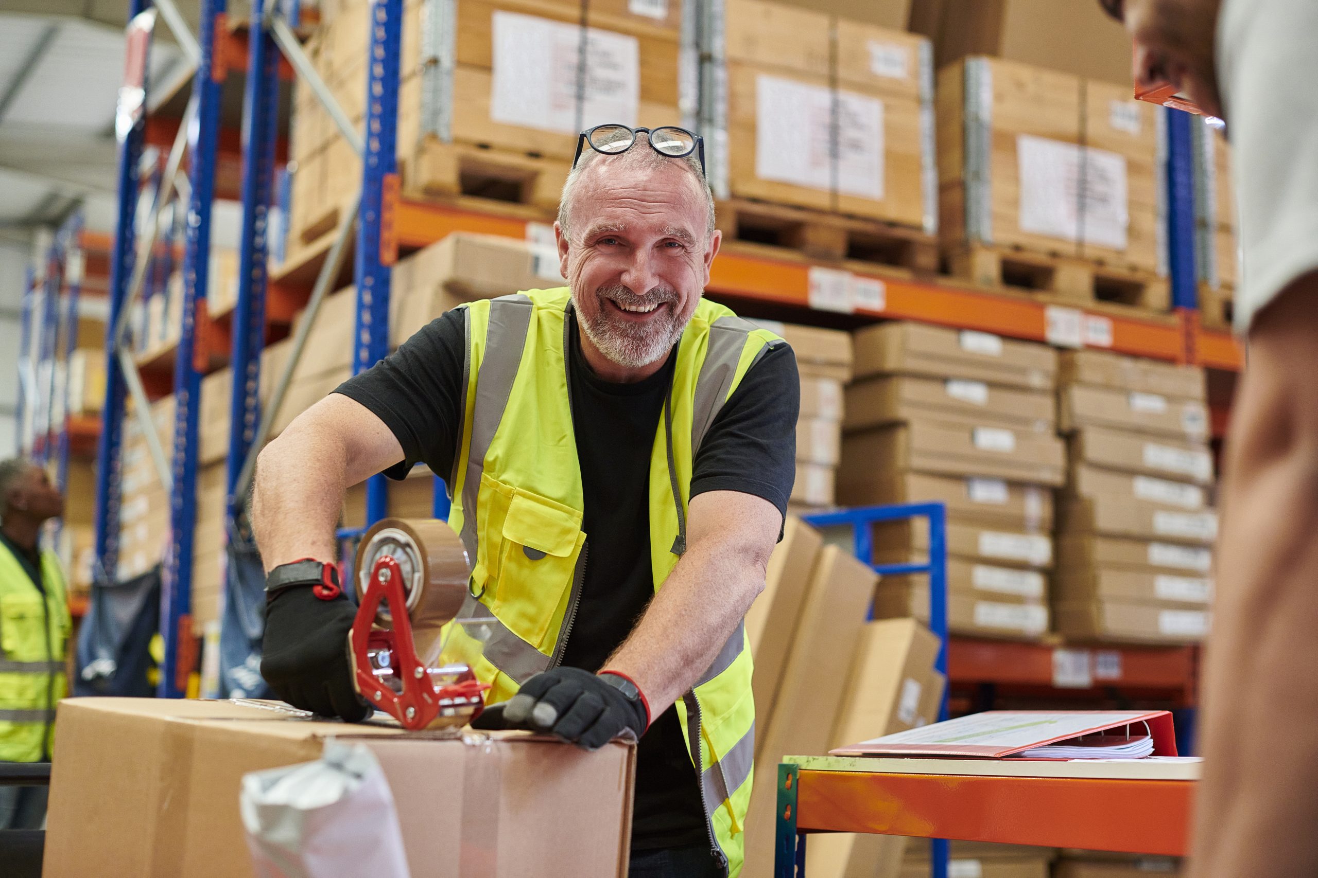 Man smiling while packaging a box in a warehouse